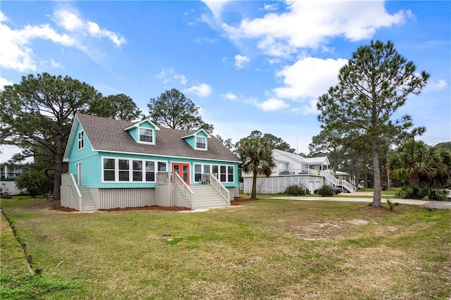 view of front of property featuring a front lawn, stairway, and a shingled roof