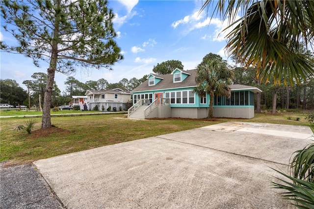 view of front facade with a sunroom, a front yard, concrete driveway, and a shingled roof