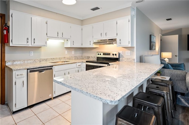 kitchen with appliances with stainless steel finishes, under cabinet range hood, a peninsula, white cabinets, and a sink