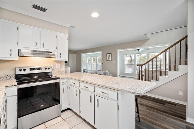 kitchen with stainless steel range with electric stovetop, under cabinet range hood, a peninsula, white cabinetry, and recessed lighting