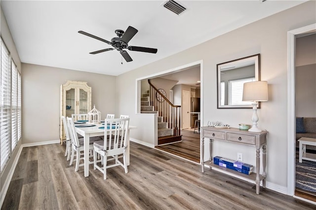 dining space featuring stairway, wood finished floors, baseboards, and ceiling fan