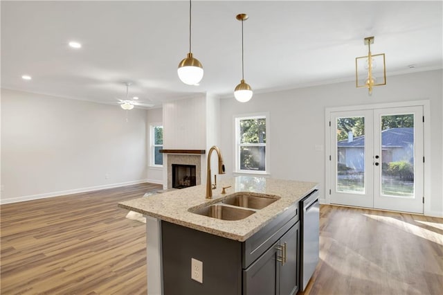 kitchen featuring light stone countertops, french doors, stainless steel dishwasher, sink, and pendant lighting