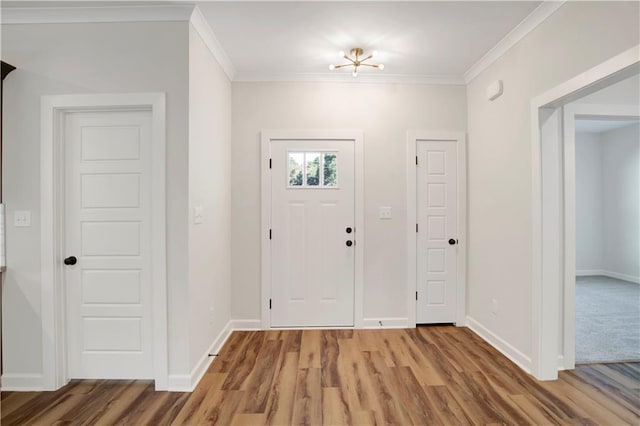 entryway with wood-type flooring, crown molding, and a chandelier