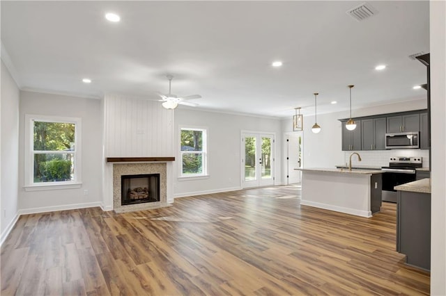 kitchen with a wealth of natural light, crown molding, appliances with stainless steel finishes, and dark wood-type flooring