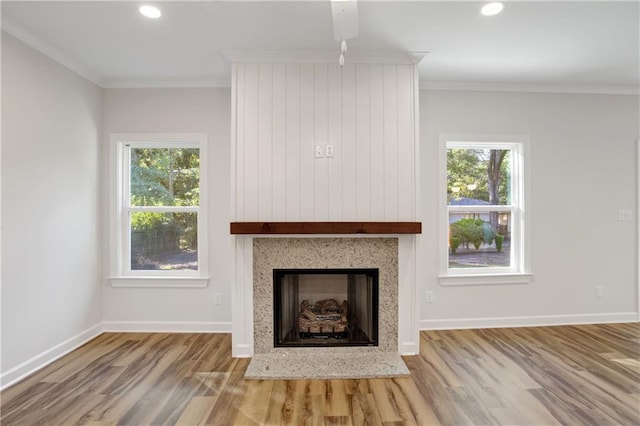 unfurnished living room featuring wood-type flooring, a wealth of natural light, and crown molding