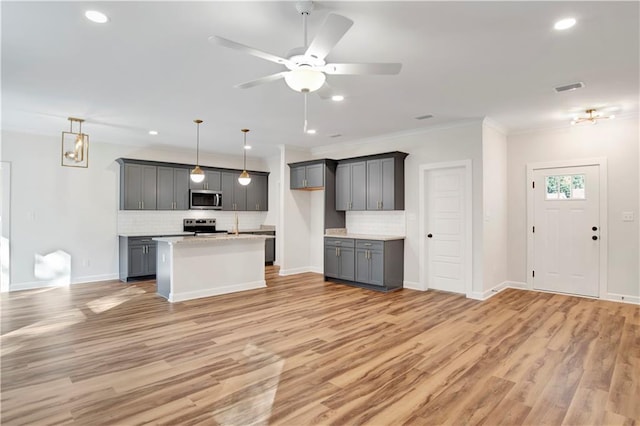 kitchen featuring appliances with stainless steel finishes, light wood-type flooring, tasteful backsplash, gray cabinetry, and hanging light fixtures