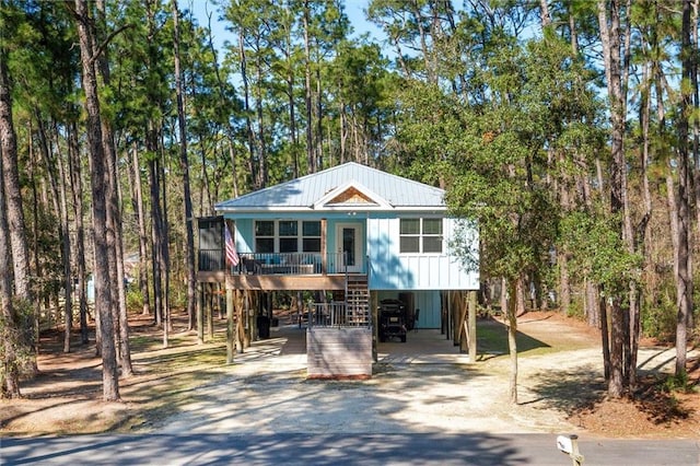 coastal inspired home with stairs, a carport, a porch, and driveway