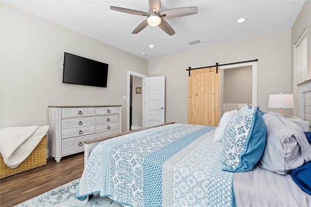 bedroom featuring ceiling fan, a barn door, recessed lighting, visible vents, and dark wood finished floors