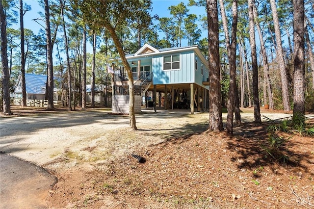 coastal inspired home with stairs, driveway, a carport, and board and batten siding