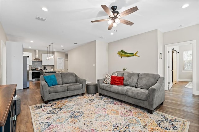 living room featuring ceiling fan, recessed lighting, dark wood-style flooring, visible vents, and baseboards