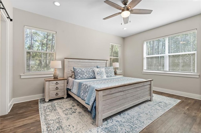 bedroom featuring a barn door, recessed lighting, dark wood finished floors, and baseboards