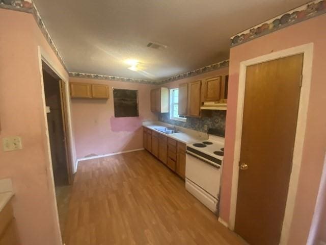 351 Lincoln Blvd, Mobile, AL 36608 - kitchen featuring white range with electric cooktop, light wood-style flooring, under cabinet range hood, backsplash, and light countertops