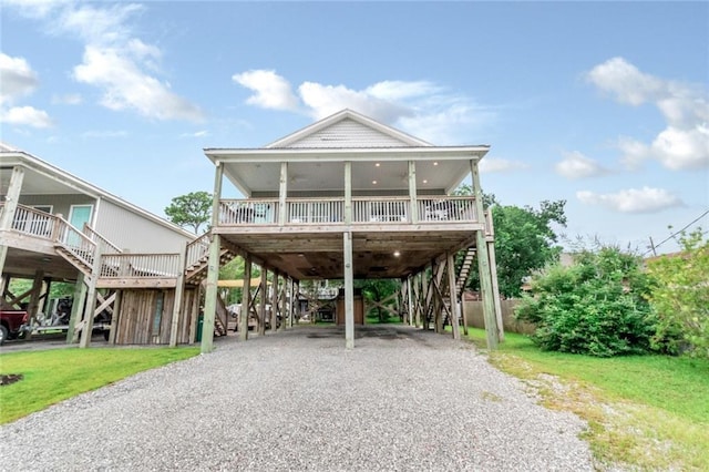 raised beach house with a front yard, a carport, and covered porch