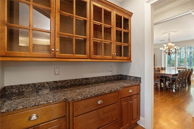 6060 Riverchase Dr S, Mobile, AL 36619 - kitchen with a chandelier, brown cabinetry, wood finished floors, glass insert cabinets, and crown molding
