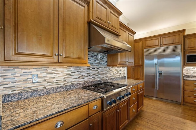 6060 Riverchase Dr S, Mobile, AL 36619 - kitchen featuring built in appliances, under cabinet range hood, tasteful backsplash, brown cabinetry, and ornamental molding