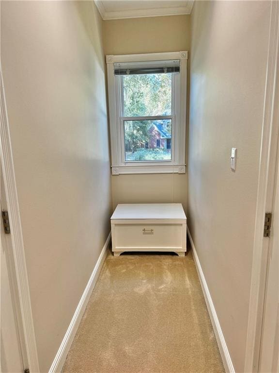 hallway with light colored carpet and crown molding