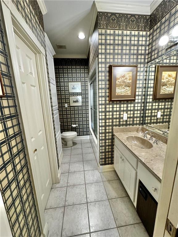 bathroom featuring vanity, tile patterned floors, crown molding, toilet, and a shower with shower door