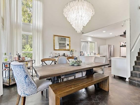 tiled dining room featuring a chandelier and a towering ceiling