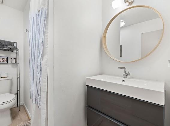 bathroom with toilet, large vanity, and hardwood / wood-style floors