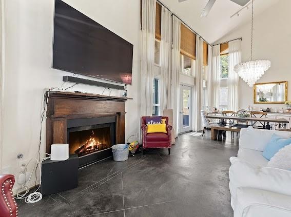 living room with high vaulted ceiling and ceiling fan with notable chandelier