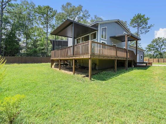 back of property featuring a wooden deck and a yard