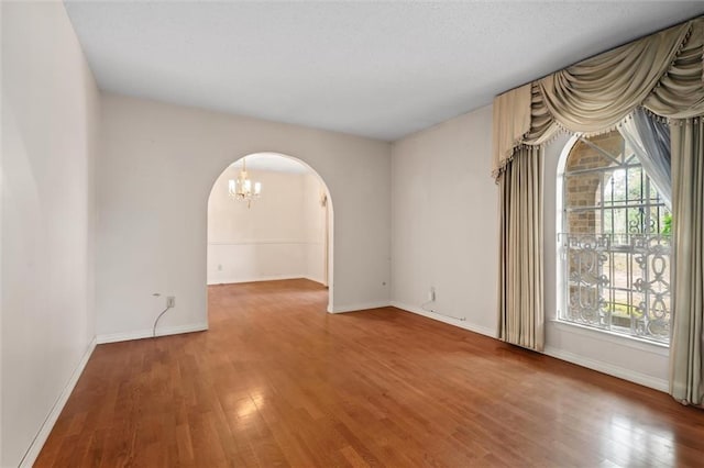 spare room with an inviting chandelier and hardwood / wood-style floors