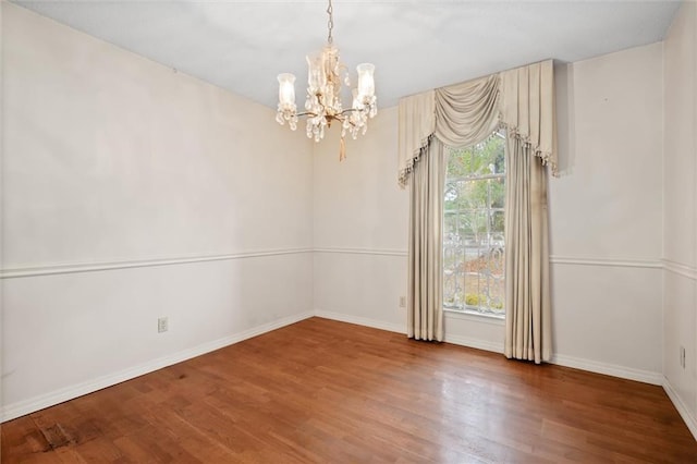 unfurnished room featuring hardwood / wood-style flooring and a chandelier