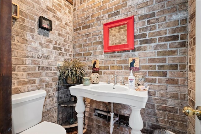 bathroom with brick wall and toilet