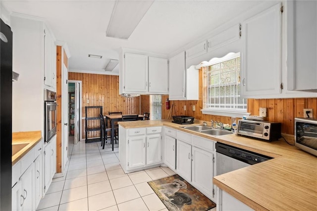 kitchen featuring sink, appliances with stainless steel finishes, wooden walls, white cabinets, and kitchen peninsula