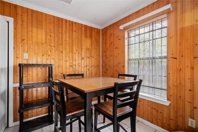 dining space with crown molding, wooden walls, and light tile patterned flooring