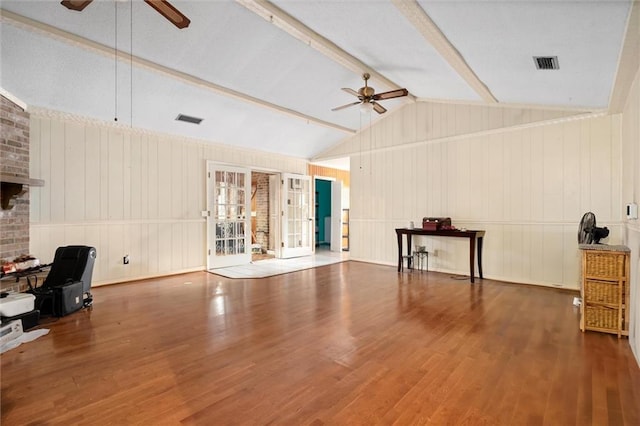 unfurnished living room featuring a fireplace, wood-type flooring, lofted ceiling with beams, and ceiling fan