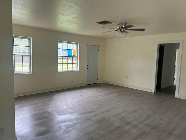 empty room featuring wood finished floors, baseboards, and a ceiling fan