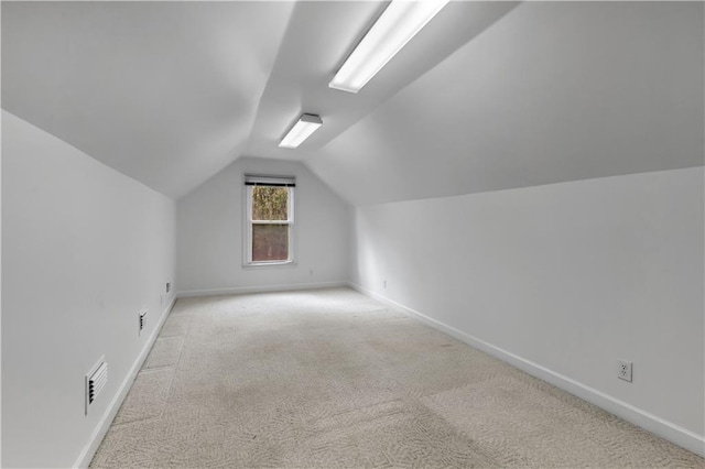 additional living space featuring light colored carpet and lofted ceiling