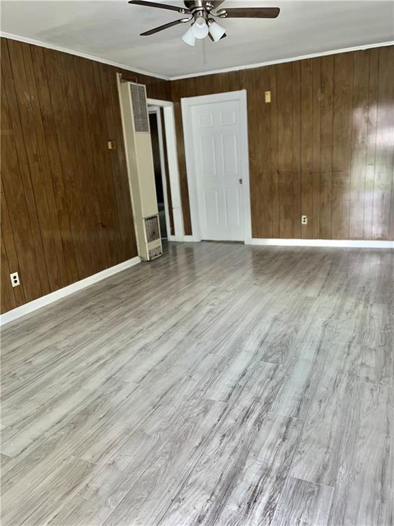 1053 Lubel Ave, Mobile, AL 36617 - spare room featuring a ceiling fan, a heating unit, wood finished floors, and wooden walls