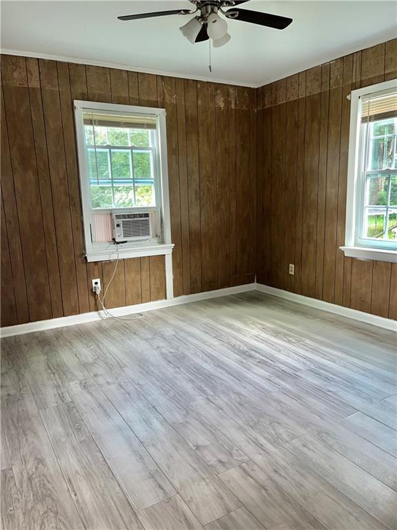 1053 Lubel Ave, Mobile, AL 36617 - empty room featuring a ceiling fan, wood finished floors, wooden walls, and cooling unit