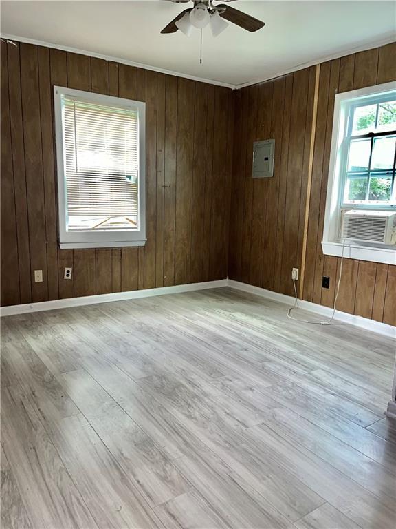 1053 Lubel Ave, Mobile, AL 36617 - unfurnished room with ceiling fan, light wood-style flooring, cooling unit, electric panel, and wood walls