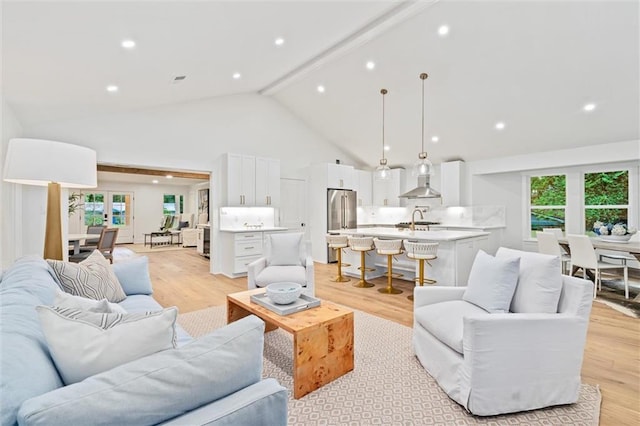 living room featuring beam ceiling, sink, high vaulted ceiling, and light hardwood / wood-style floors