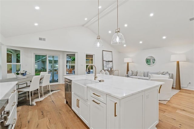 kitchen featuring white cabinetry, sink, hanging light fixtures, beamed ceiling, and an island with sink