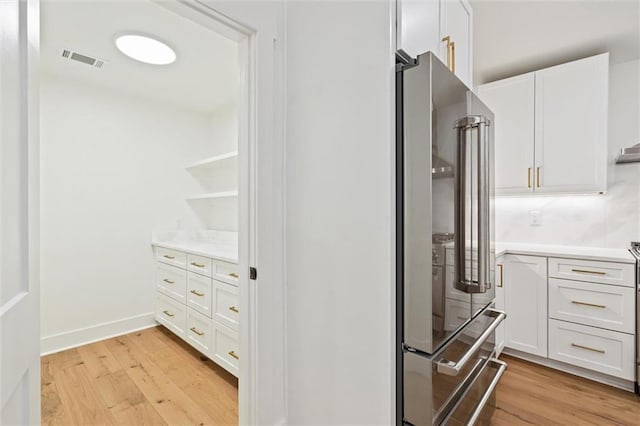 kitchen with high end refrigerator, white cabinetry, and light hardwood / wood-style flooring