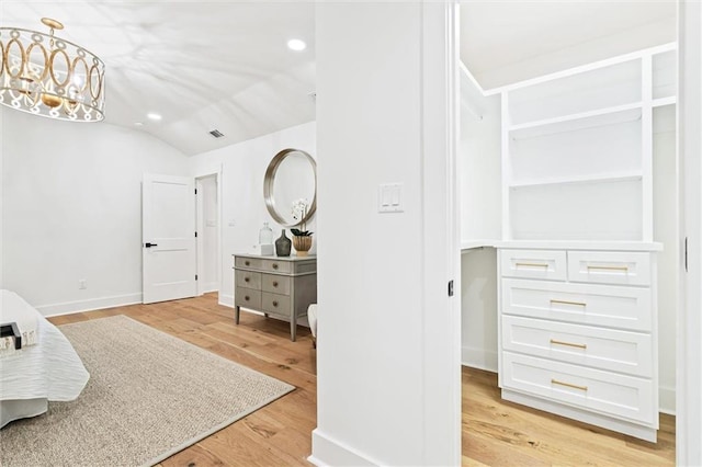 bedroom with a chandelier, light wood-type flooring, and vaulted ceiling