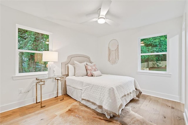 bedroom featuring multiple windows, hardwood / wood-style flooring, and ceiling fan