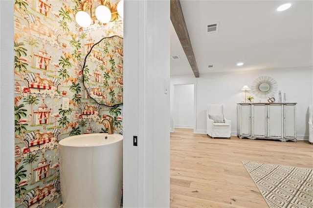 bathroom featuring hardwood / wood-style floors, beam ceiling, and an inviting chandelier