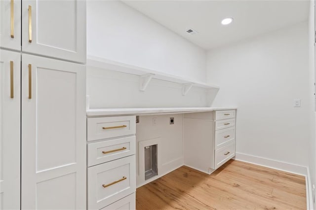 laundry room with electric dryer hookup, cabinets, and light hardwood / wood-style floors