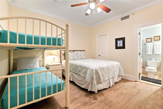 bedroom featuring baseboards, visible vents, ornamental molding, wood finished floors, and ensuite bathroom