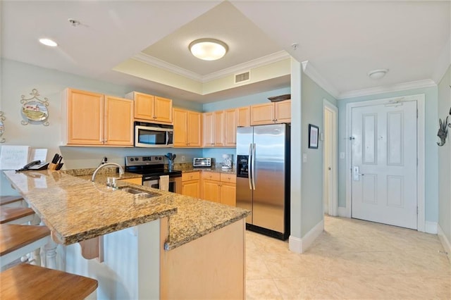 kitchen featuring visible vents, light stone counters, a peninsula, stainless steel appliances, and light brown cabinetry