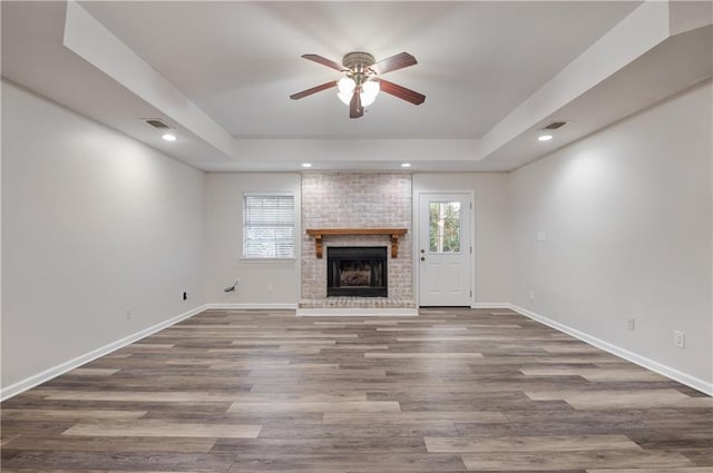 unfurnished living room with hardwood / wood-style floors, plenty of natural light, and a raised ceiling