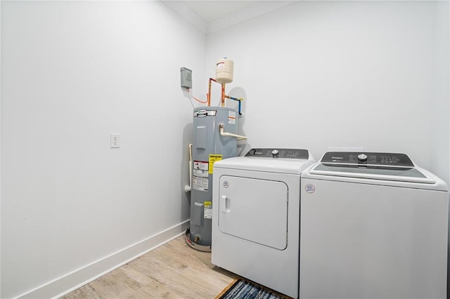 clothes washing area featuring water heater, light hardwood / wood-style flooring, crown molding, and washer and dryer