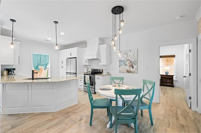 kitchen featuring white cabinets, white refrigerator, hanging light fixtures, stainless steel range with electric stovetop, and light hardwood / wood-style flooring