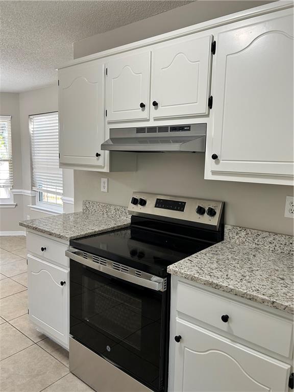 3120 Wellborne Dr W, Mobile, AL 36695 - kitchen with stainless steel range with electric stovetop, under cabinet range hood, white cabinetry, and a textured ceiling