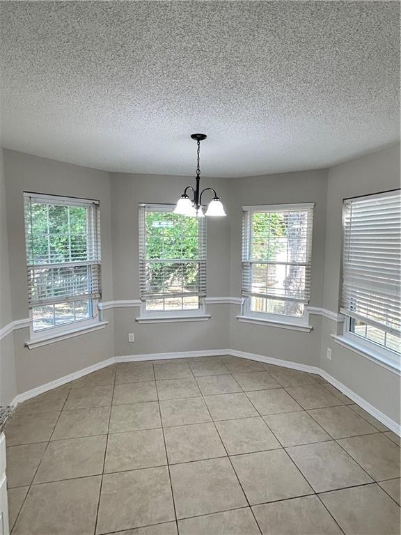 3120 Wellborne Dr W, Mobile, AL 36695 - empty room featuring light tile patterned flooring, a chandelier, healthy amount of natural light, a textured ceiling, and baseboards
